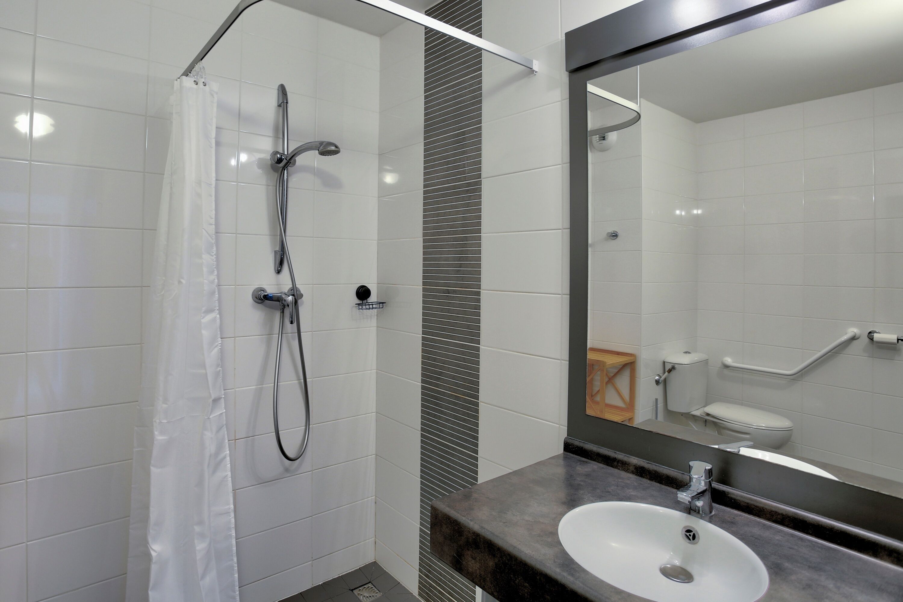 A modern bathroom with a shower, toilet, and sink.