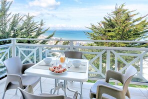 Un balcón con mesa dispuesta para el desayuno, con vistas a la costa.