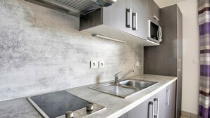 Une cuisine moderne dotée d’une plaque de cuisson intégrée, d’un évier et d’un four à micro-ondes.