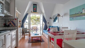 A cozy room with a dining area, kitchen, and a large window.