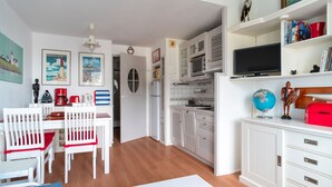 A compact living space with a dining area, kitchenette, and a TV on a cabinet.