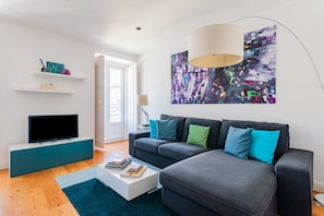 A modern living room with a flat-screen TV, a sofa, a coffee table, and a large abstract painting on the wall. - Lisbon Prime Apartment (Lisbon)