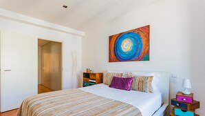 A bedroom with a bed, a nightstand, a painting, and a wardrobe. - Lisbon Prime Apartment (Lisbon)