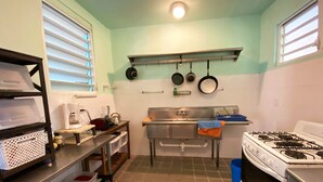 A compact kitchen with a gas stove, a coffee maker, and a sink.