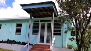 A two-story building with a light blue exterior, a covered porch with a roof, and a staircase leading to the entrance.