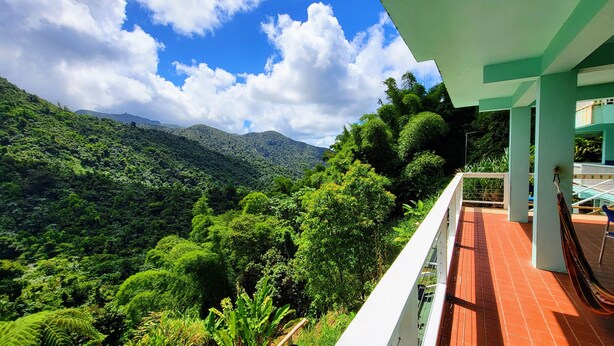 A balcony with a view of a lush green landscape and mountains.
