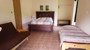 A bedroom with two beds, a wooden bench, a small table, and a ceiling fan.