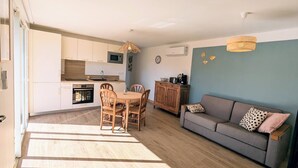A modern apartment with a kitchen, dining area, and living room. - Jasmin - Nature & sea with terrace and play area (Lesperon)