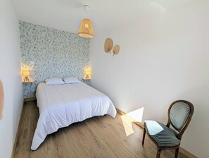 A bedroom with a bed, two wall-mounted lamps, a chair, and a patterned wallpaper.