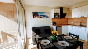 A modern kitchen with white cabinets, a built-in oven, and a coffee maker. - Appartement T2 Front de mer (Mimizan)