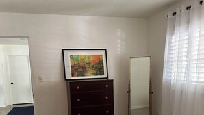 A bedroom with a bed, dresser, framed artwork, and a ceiling fan. - Quaint Key West Pool Bungalow (Winter Park)
