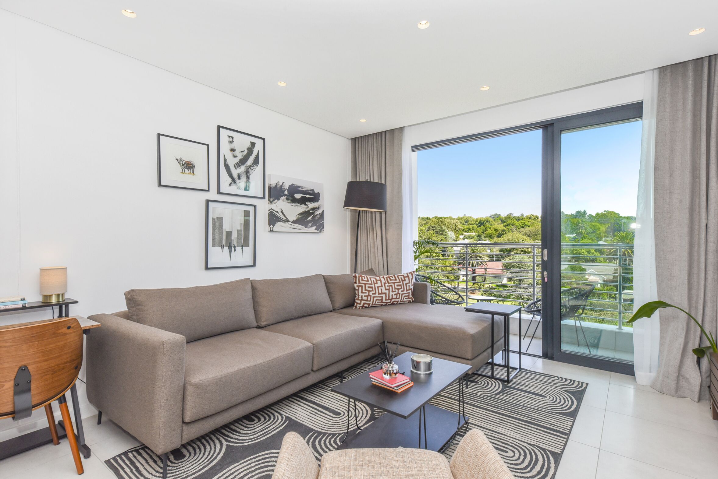 A modern living room with a sectional sofa, a coffee table, and artwork on the walls.
