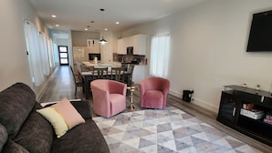 A modern living room with a dark brown sofa, a patterned rug, and a ceiling fan. - Dallas Home (Dallas)