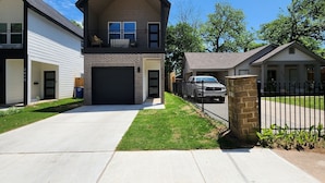 A two-story house with a garage, a front lawn, and a stone pillar. - Dallas Home (Dallas)