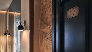 Ett hotellrum med en mörk dörr, en stenmur och en nummerskylt som visar att det är rum 1.2.