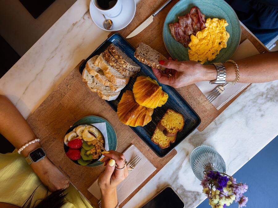 Una mesa de desayuno con diferentes alimentos, una taza de café y un teléfono inteligente.