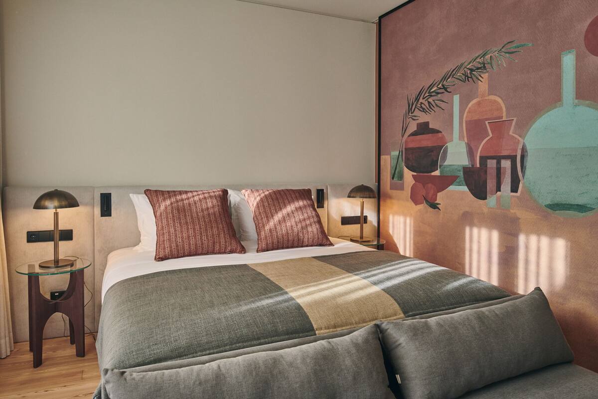 Un dormitorio con una cama grande, dos lámparas de noche y un mural en la pared.