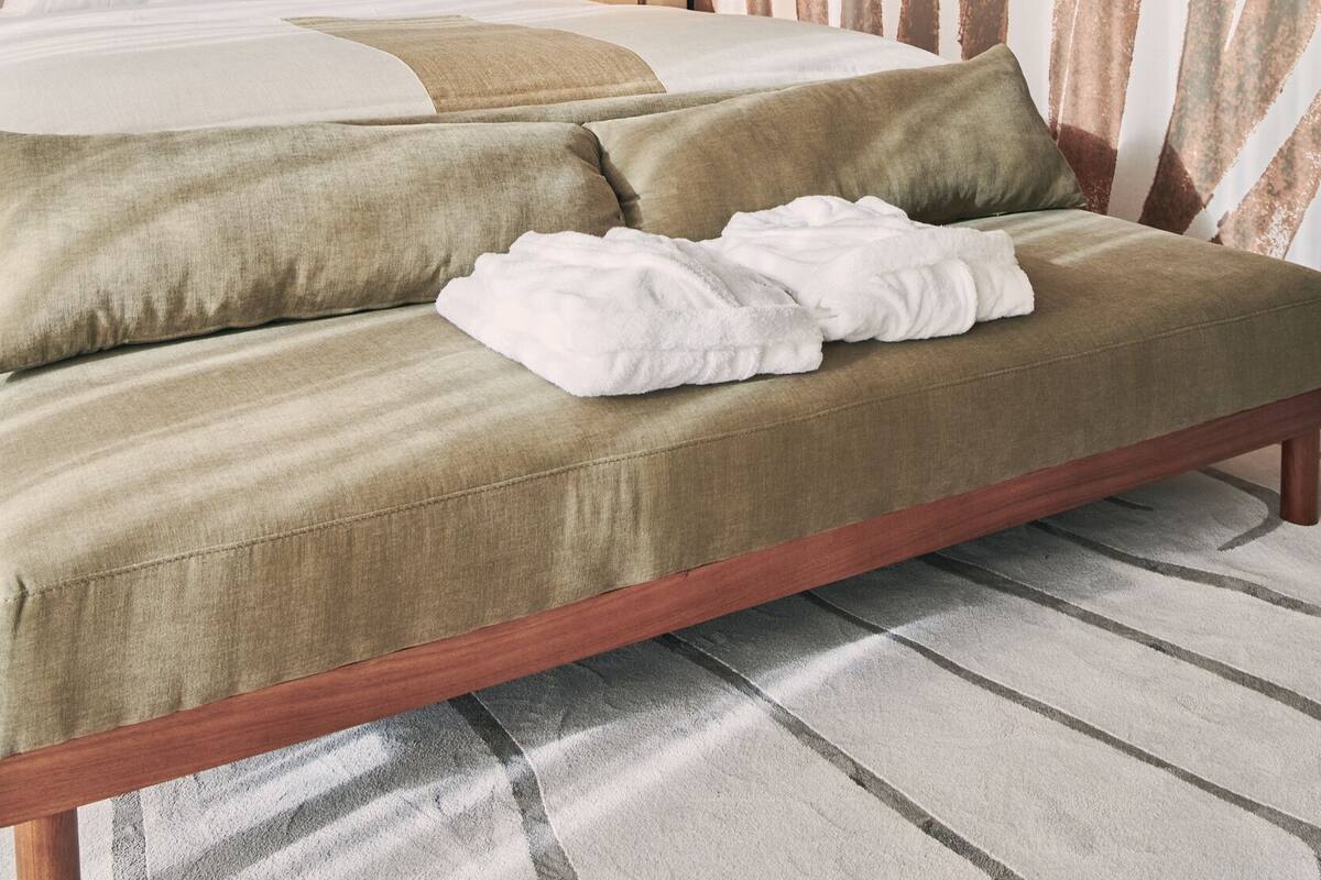 Una habitación de hotel moderna con una cama grande, una mesita de noche y un cuadro abstracto de gran tamaño en la pared.