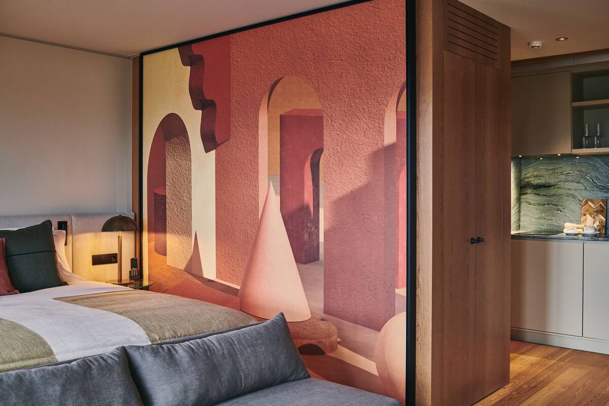 Un dormitorio moderno con una cama grande, una mesita de noche y una lámpara de pared.