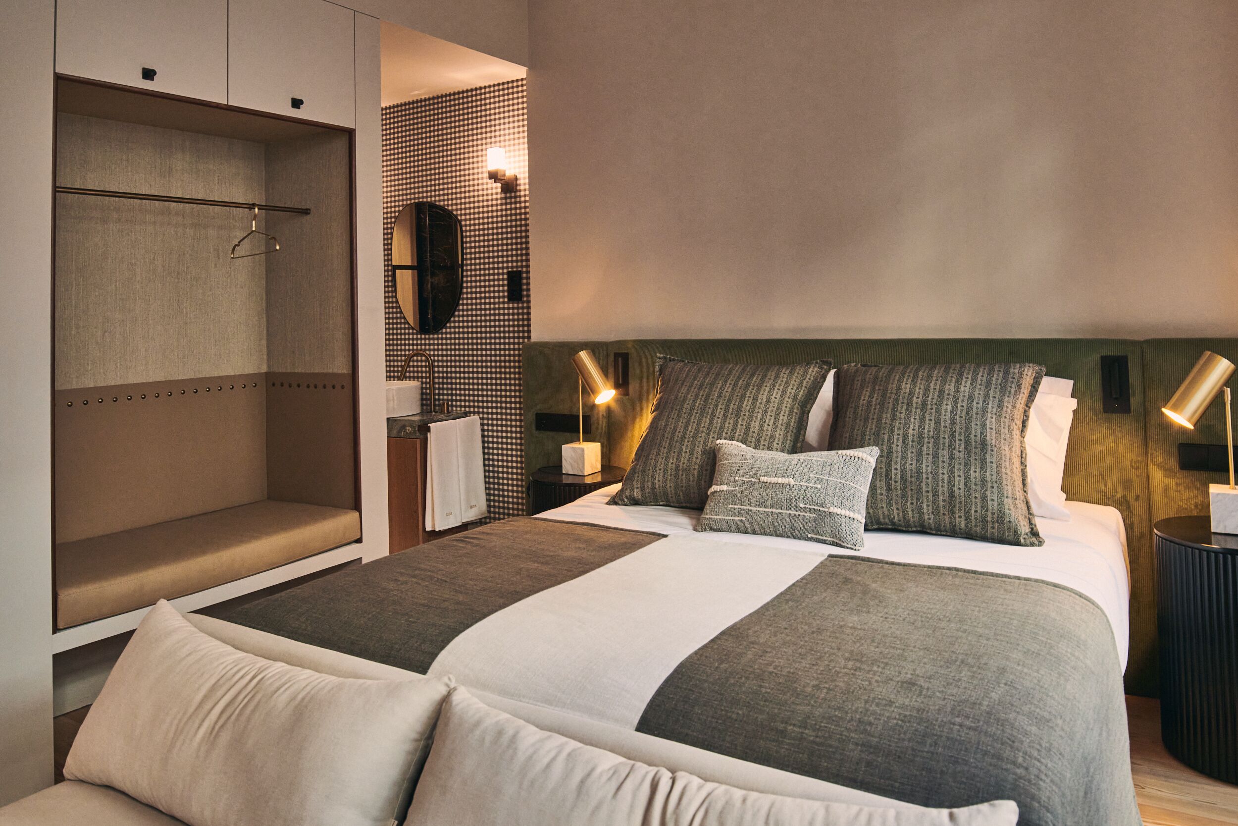 A modern hotel room with a large bed, a seating area, and a mirror.