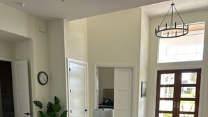 Un ampio soggiorno con un grande divano angolare grigio, una pianta in vaso e un lampadario moderno.