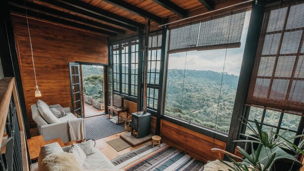 Una habitación acogedora con un ventanal grande, chimenea y vistas al bosque.