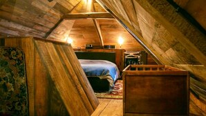 A cozy attic bedroom with a bed, a wooden chest, and a rug. - Les Maisons du Bonheur & Balnéo (Croze)