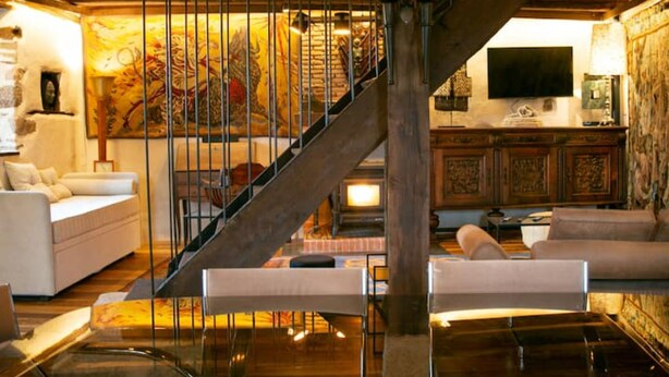 A spacious living area with a staircase, a fireplace, and a television. - Les Maisons du Bonheur & Balnéo (Croze)