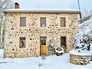 Un edificio de piedra con puerta de madera y varias ventanas, rodeado de nieve.