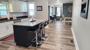 A modern kitchen with a large island, bar stools, and a dining area with a table and chairs. - Beautiful Country Setting Welcome to Moberly Manor (Depauw)