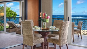 Un coin repas avec des chaises en osier et une table en verre, donnant sur l’océan.