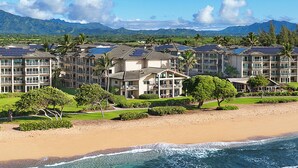 Un hôtel situé en bord de mer, composé de plusieurs bâtiments, doté de panneaux solaires et donnant sur une plage de sable.
