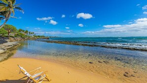 Une plage avec une eau cristalline, un palmier et une rangée de chaises de plage.