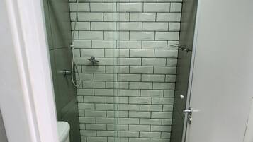Un baño pequeño con inodoro, cabina de ducha de vidrio y pared de azulejos.