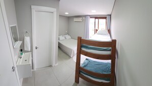 Quarto com cama beliche, mesa de cabeceira, espelho e ar condicionado.