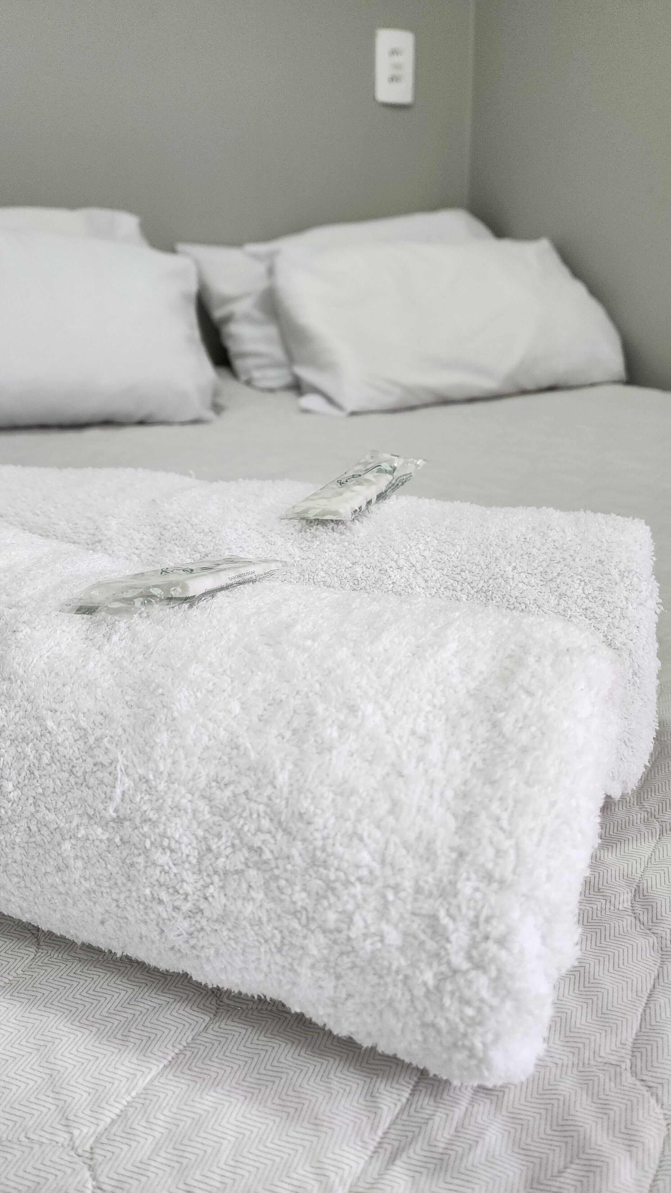 A neatly made bed with white linens and a folded towel.