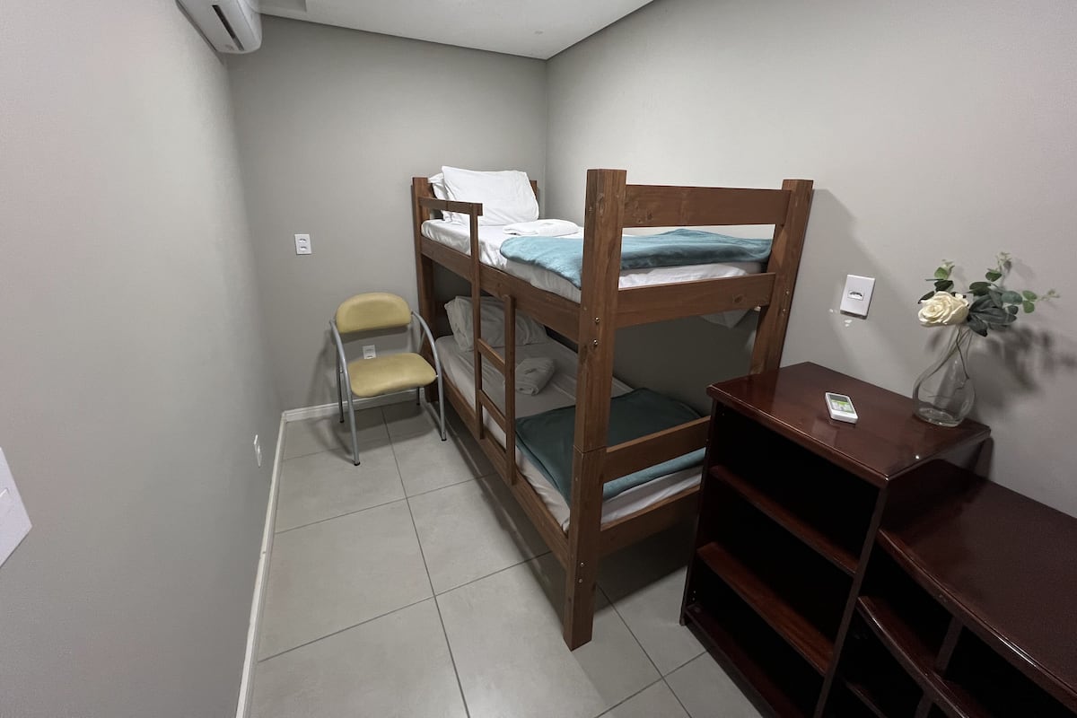 A bunk bed room with a chair and a small table.