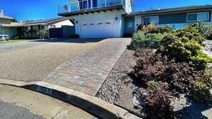 A two-story house with a garage, a paved driveway, and a small garden with shrubs. - Ocean View Home w/PrivateBalcony (Carlsbad)