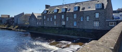 A stone building with multiple windows and a water channel in front.