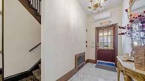 Un pasillo con una escalera de madera, una mesa ornamentada y una puerta señalizada con 