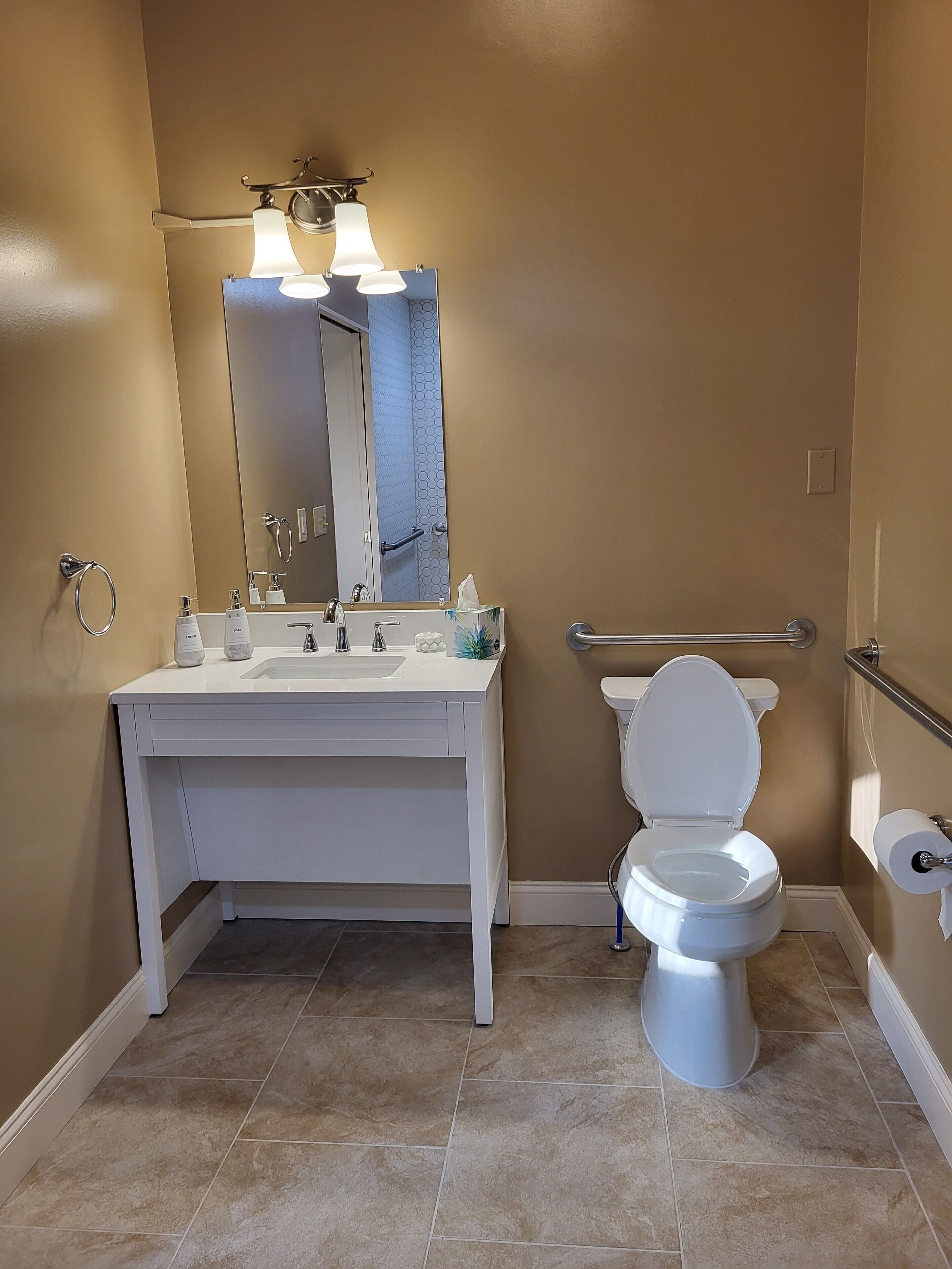 A modern bathroom with a white vanity, a toilet, and a mirror.