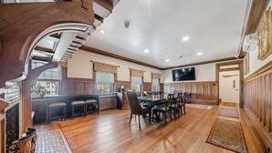 Un comedor amplio con techo alto, piso de madera y una mesa central con sillas.