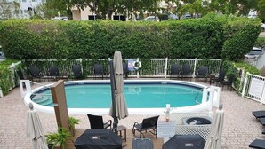An outdoor pool area with lounge chairs, a barbecue grill, and a sign with BBQ instructions. - Condo with pool, walking distance to beach, groceries and several restaurants (Pompano Beach)