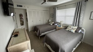 A bedroom with two beds, a ceiling fan, a TV, a desk, and a window with blinds. - Condo with pool, walking distance to beach, groceries and several restaurants (Pompano Beach)