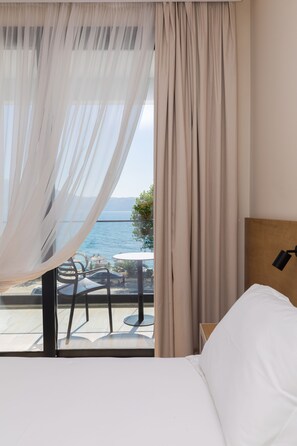 A bedroom with a bed, a bedside table, and a view of the sea through sheer curtains. - B&B Champagne Vlore Bay (Orikum)