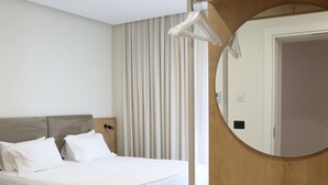 Une chambre d’hôtel avec deux lits, une coiffeuse en bois avec un miroir et un ensemble de serviettes soigneusement pliées.