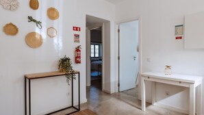 A hallway with a wooden console table, a white console table, and a fire extinguisher on the wall. - Encosta d Bidos T2 (Obidos)