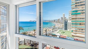 A view from a hotel window overlooking a beach with a cityscape in the background.