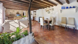 A rustic interior with exposed wooden beams, a stone fireplace, and a dining area with a table and chairs. - Es Garroverar Villa: Luxurious Retreat in the Heart of Majorca (Pollensa)