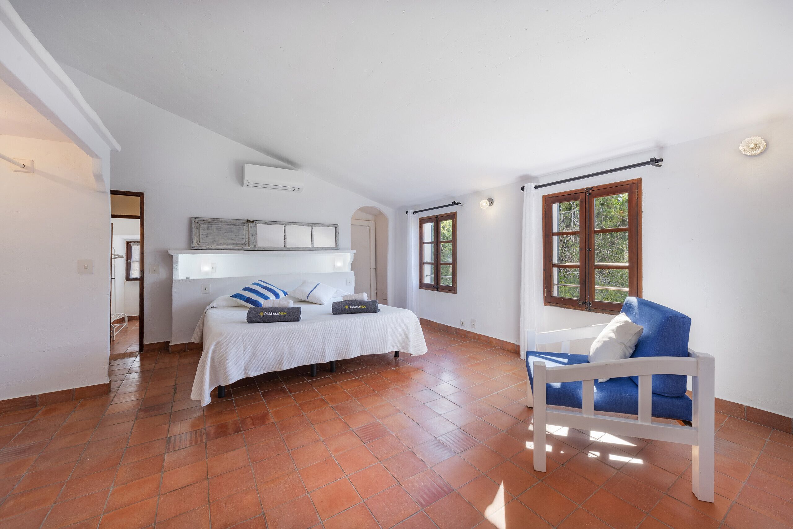 A bedroom with a bed, a chair, a window, and a door.